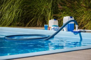 swimming-pool-vacuum-hose-brush-cleaning-water-with-maintenance-products-including-chemical Produits d'entretien sur les bords d'une piscine creusée